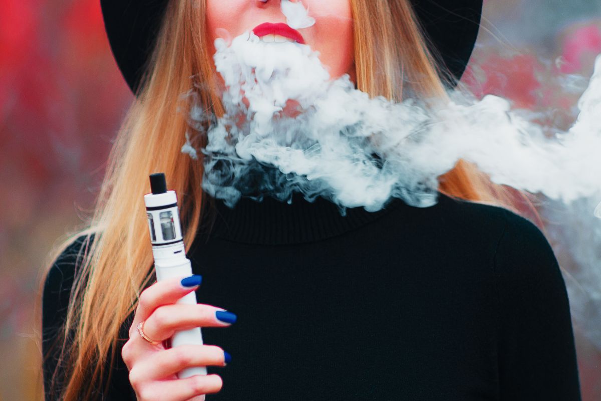 A lady vaping outdoors and enjoying